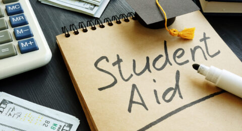 Student,Aid,Sign,With,Small,Graduation,Cap,And,Money.